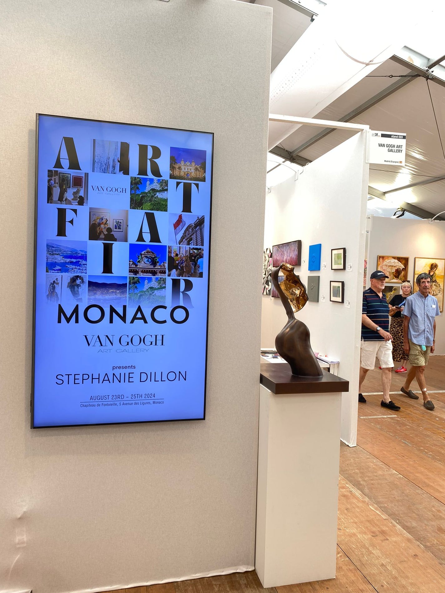 Digital display in an art gallery with a sculpture on a pedestal.